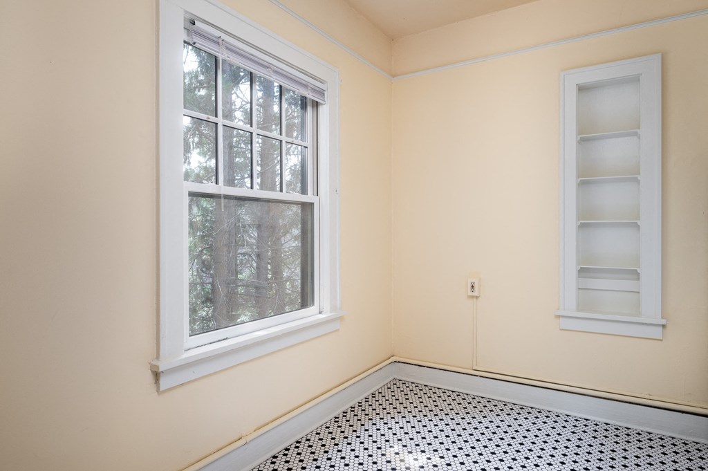 an empty room with two windows and a black and white tile floor