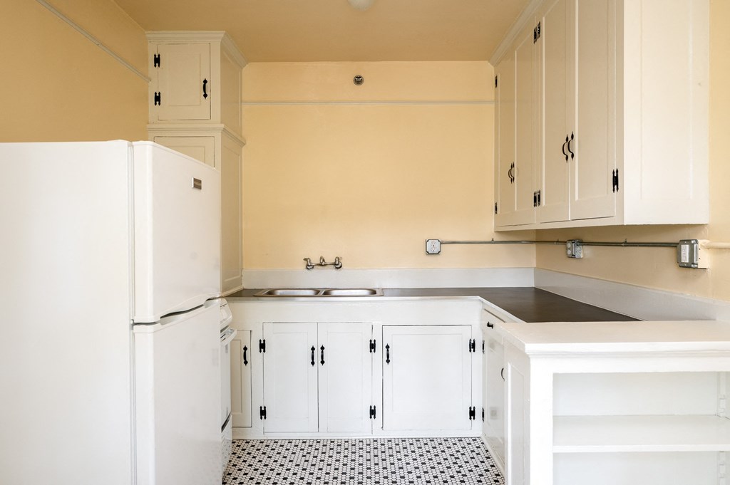 a kitchen with white cabinets and a black and white tile floor