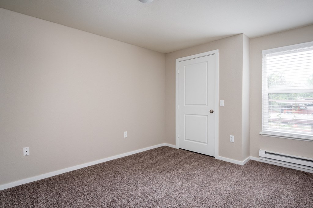 an empty bedroom with carpet and a white door