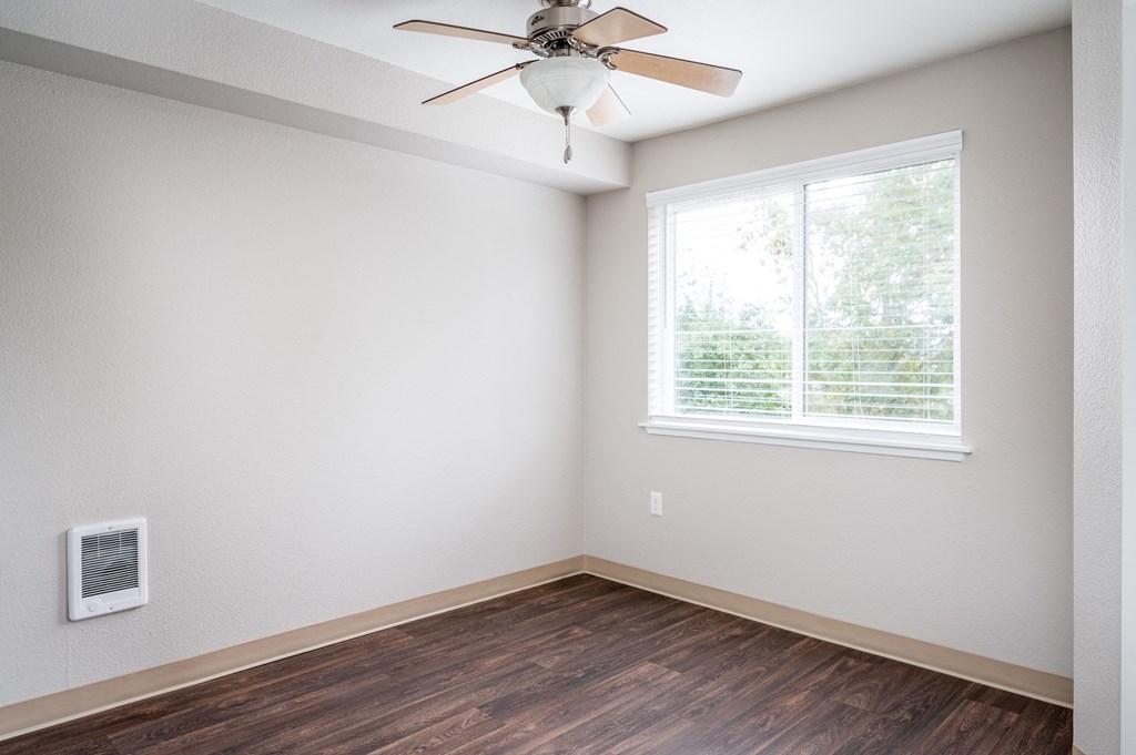 an empty room with a ceiling fan and a window