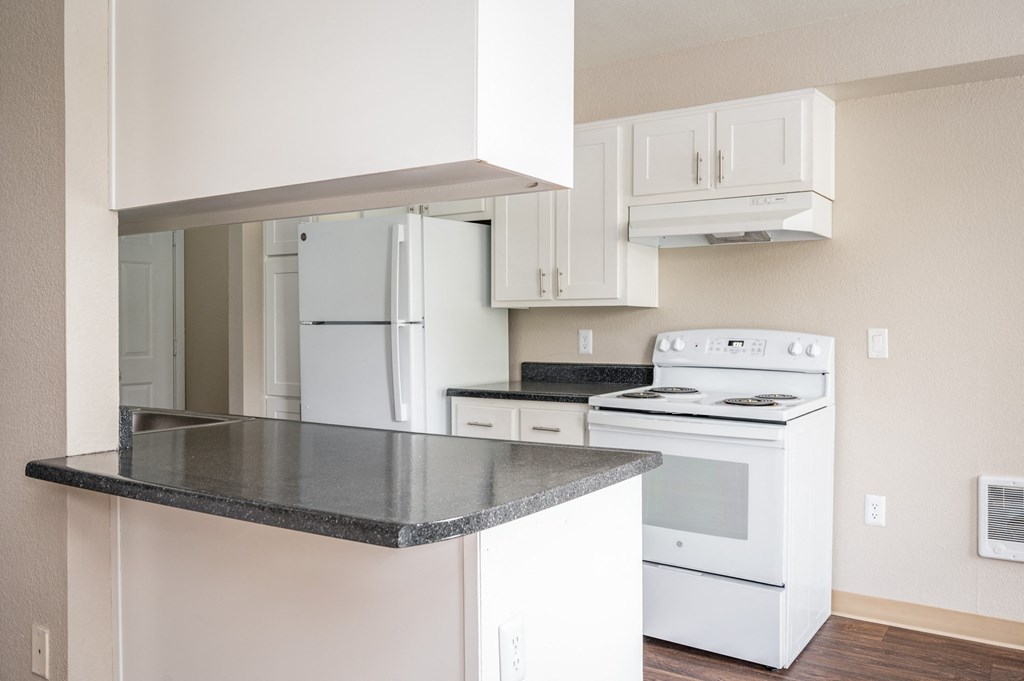 an empty kitchen with white appliances and white cabinets