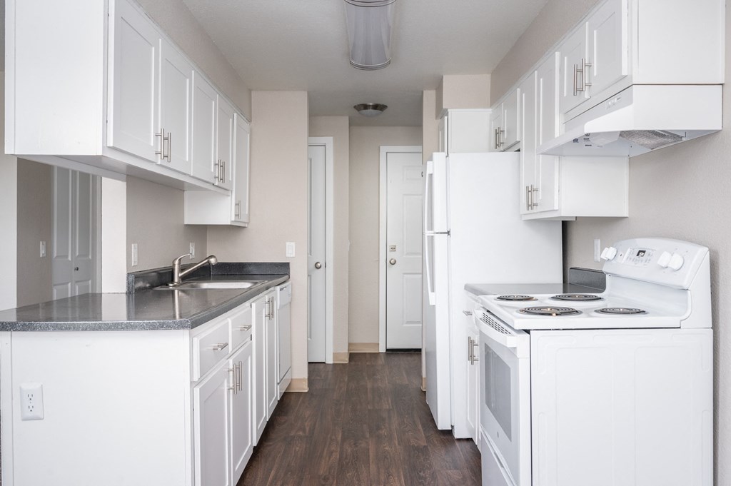 an empty kitchen with white cabinets and a white stove and refrigerator