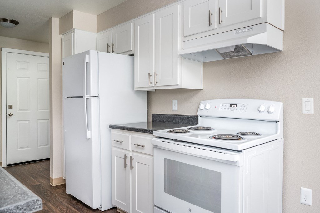 an empty kitchen with white appliances and a refrigerator