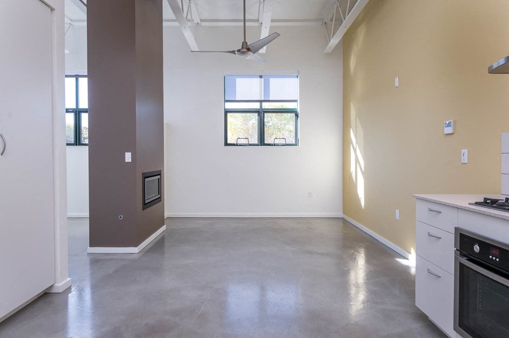 an empty kitchen and living room with a stove and a window