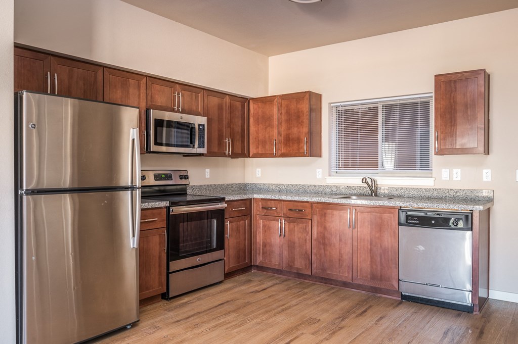 an empty kitchen with wooden cabinets and stainless steel appliances