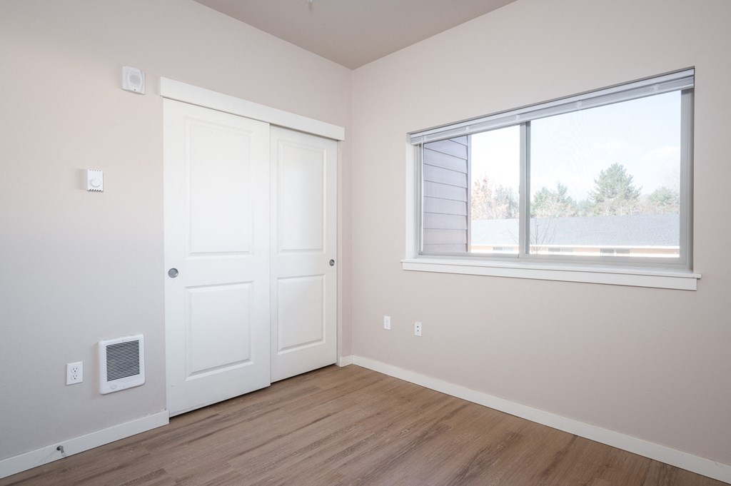 an empty bedroom with a window and a door