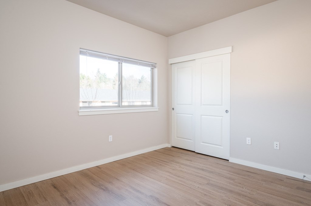 an empty room with white walls and a window and wooden floors