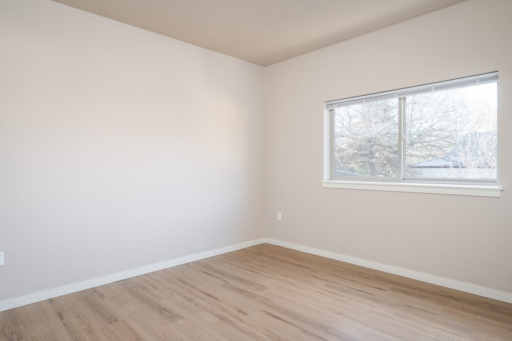 an empty room with wooden floors and a window