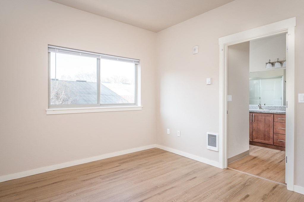 an empty bedroom with a large window and a bathroom