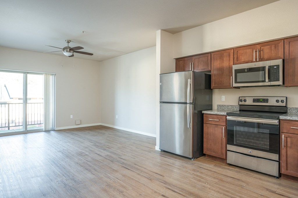 an empty kitchen with stainless steel appliances and wooden cabinets