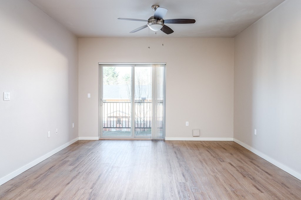 an empty living room with wooden floors and a ceiling fan