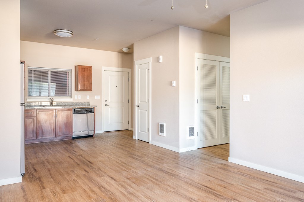 an empty kitchen and living room with wood flooring and white walls