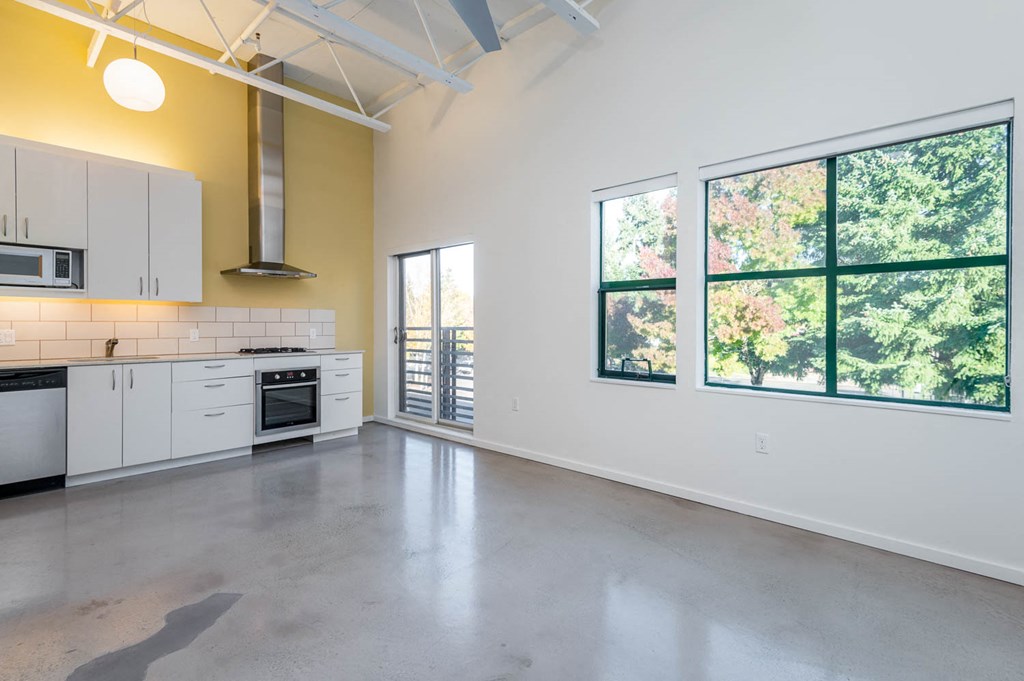 an empty kitchen with white cabinets and a large window