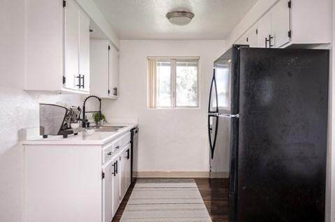 a kitchen with white cabinets and a black refrigerator
