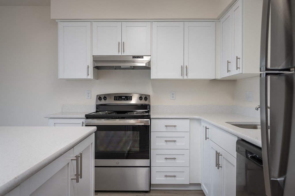 an empty kitchen with white cabinets and stainless steel appliances