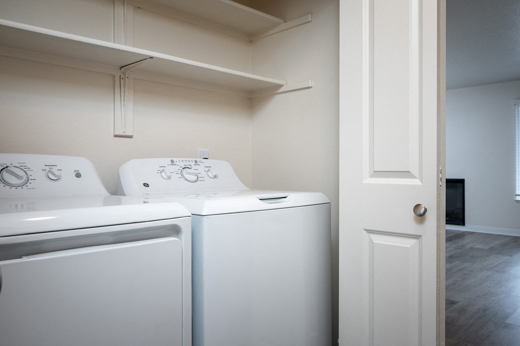 a laundry room with two washers and two dryers and a white door
