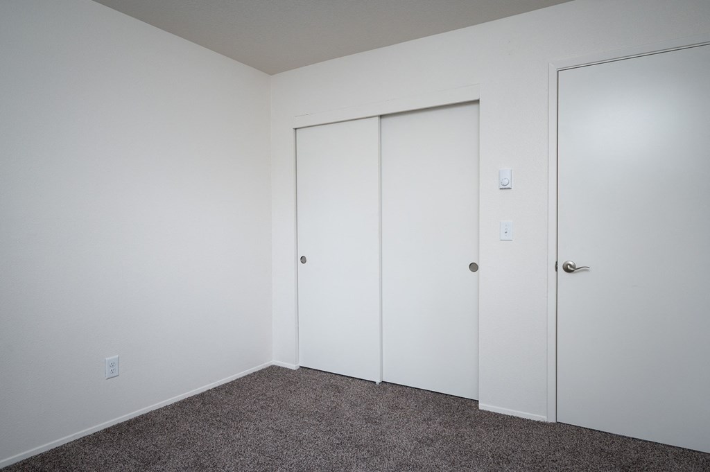 a bedroom with white walls and two closet doors