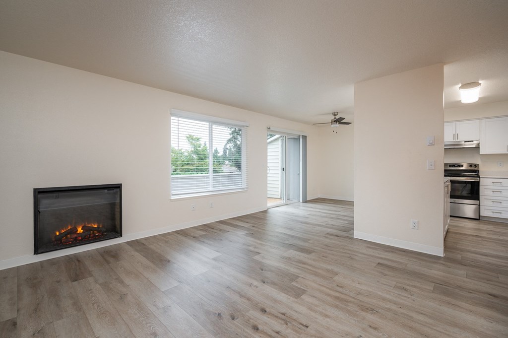 an empty living room with a fireplace and a kitchen