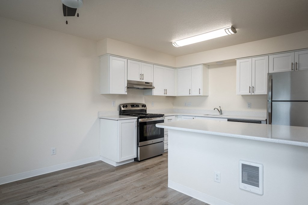 an empty kitchen with white cabinets and stainless steel appliances