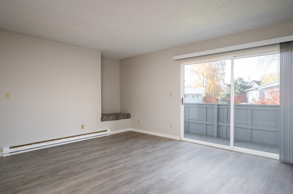 an empty living room with a sliding glass door to a balcony