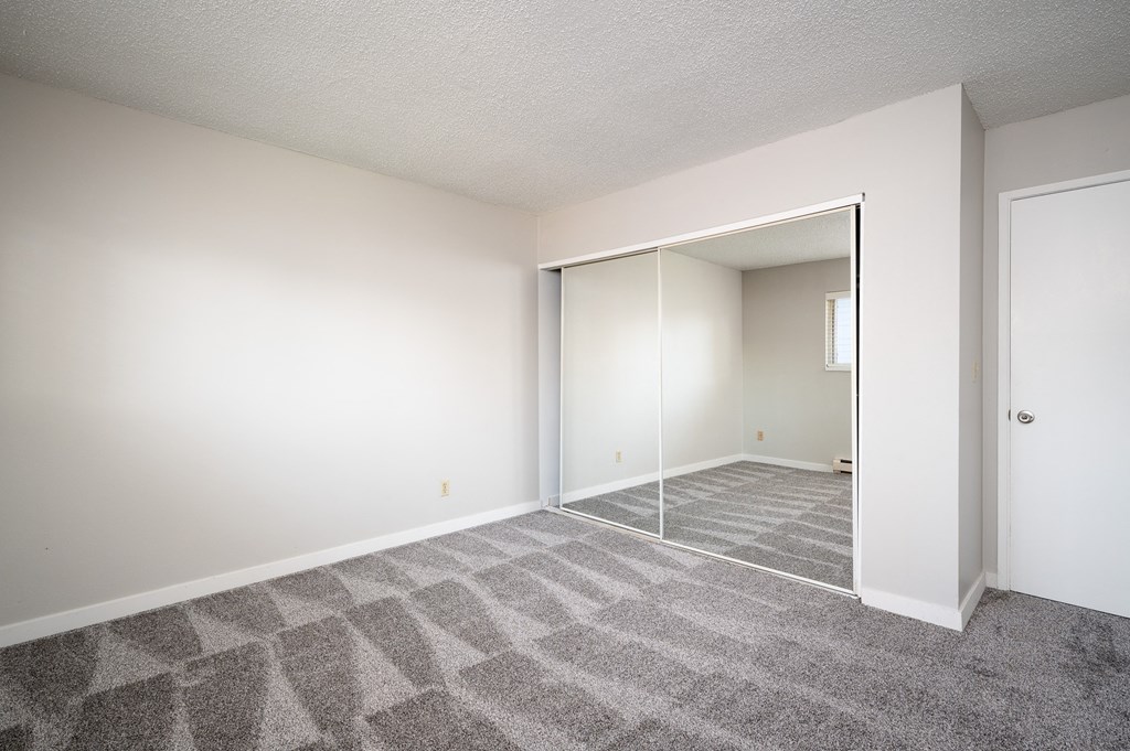 an empty living room with a door to a closet