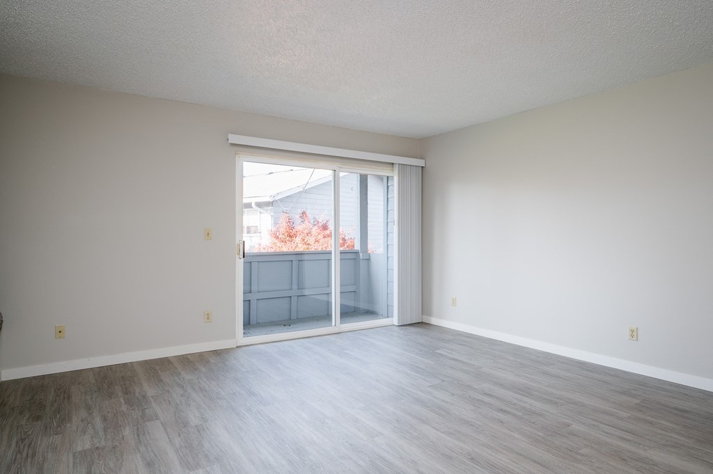an empty living room with sliding glass doors to a balcony