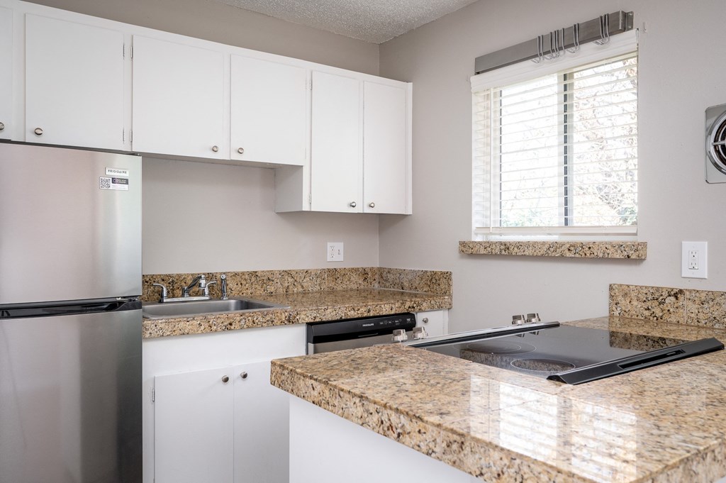 an updated kitchen with granite counter tops and white cabinets