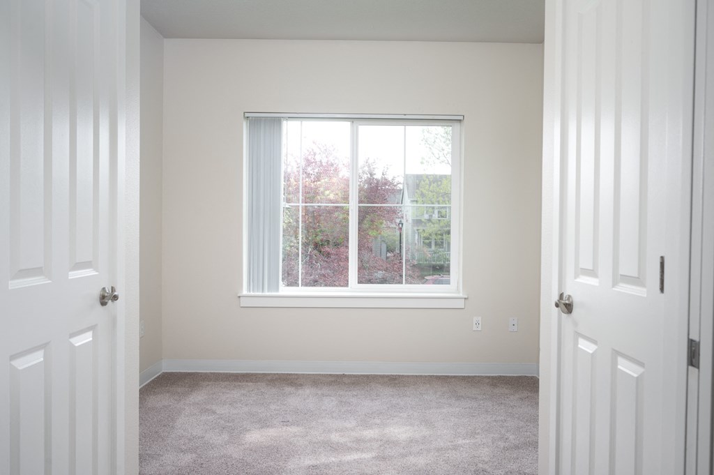 a bedroom with a large window and a carpeted floor