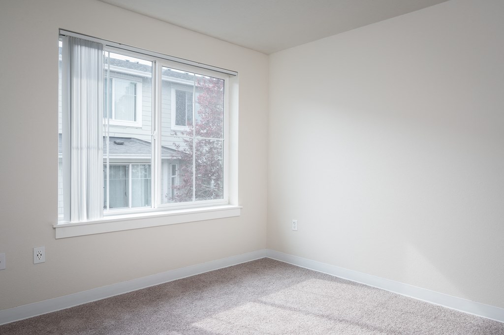 a bedroom with a large window and a carpeted floor