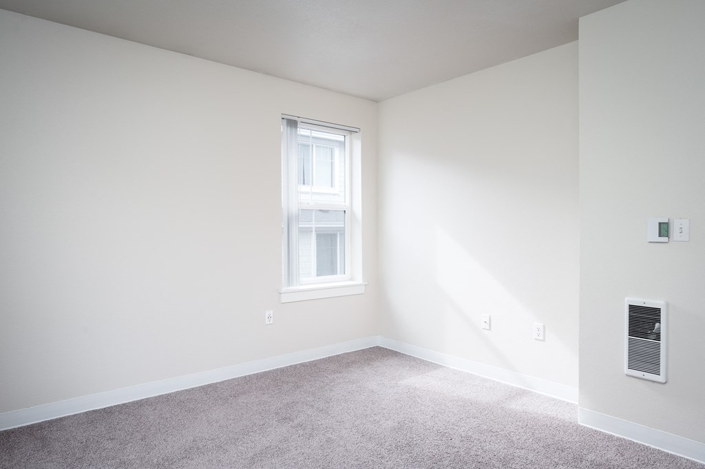 an empty room with a window and carpet
