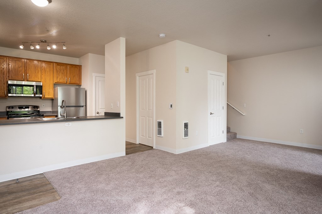 a spacious living room with a kitchen in the background