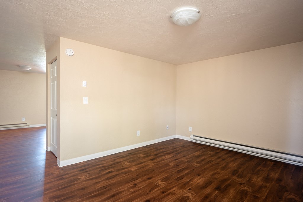 an empty living room with wood flooring and a door