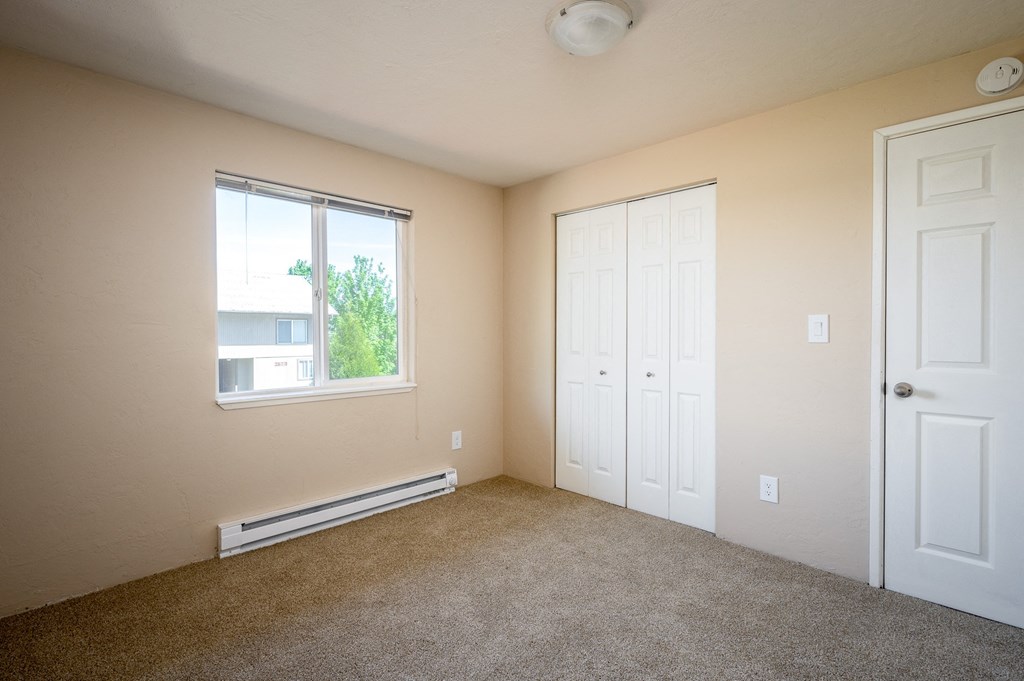 an empty room with carpet and a window and two doors