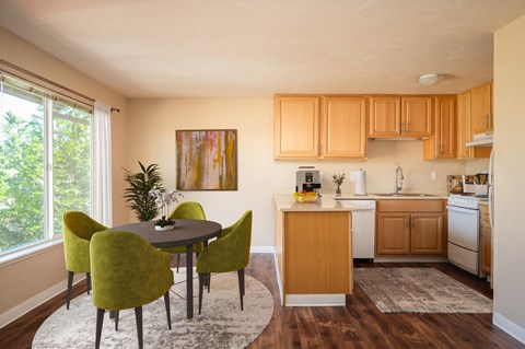 A kitchen with a table and chairs in the foreground and a painting on the wall.