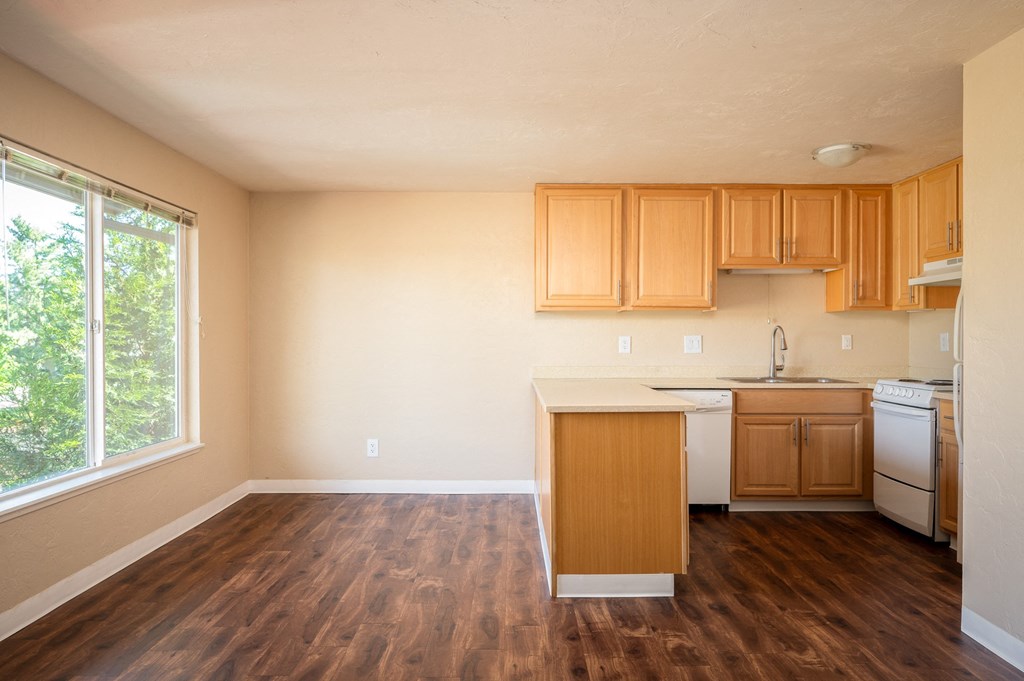 an empty kitchen with wood flooring and a large window