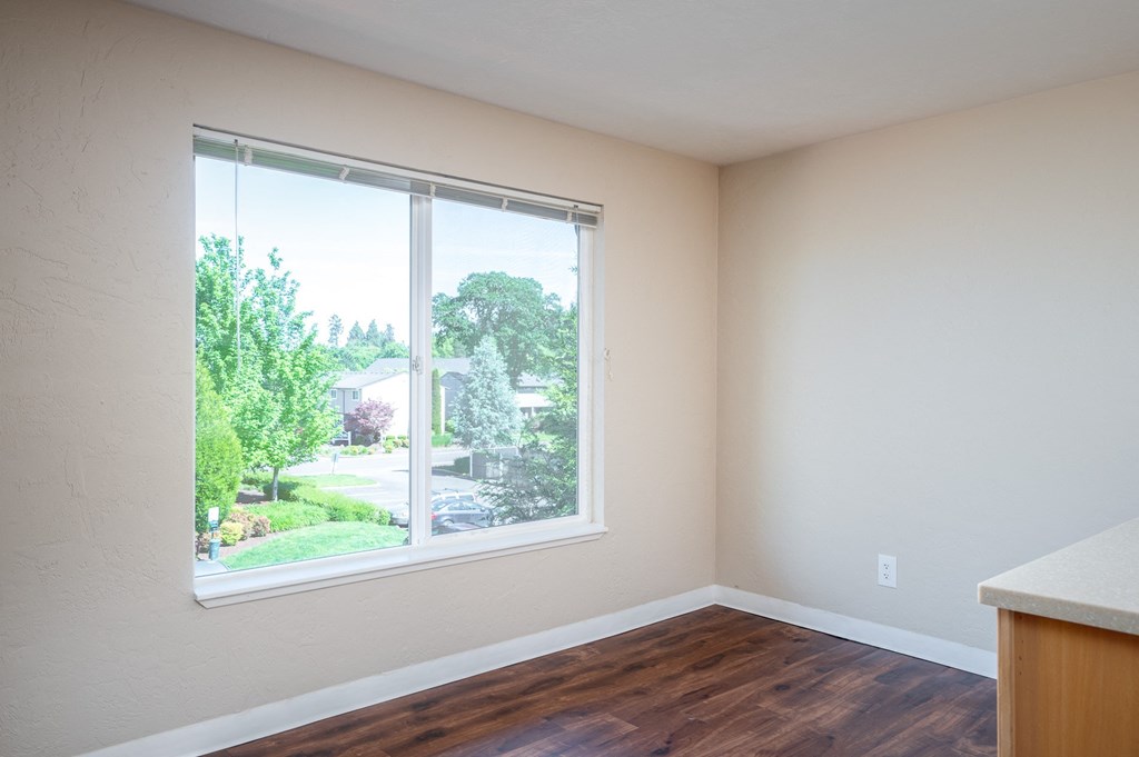 an empty room with a large window and wooden floors