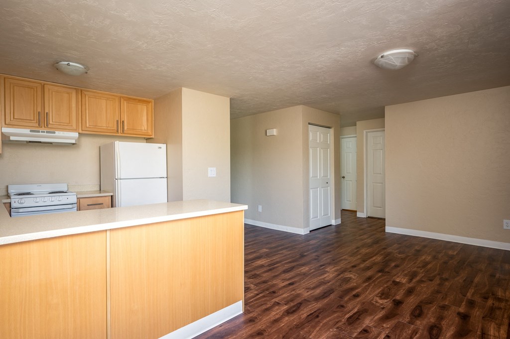 an empty kitchen with wooden floors and a white refrigerator