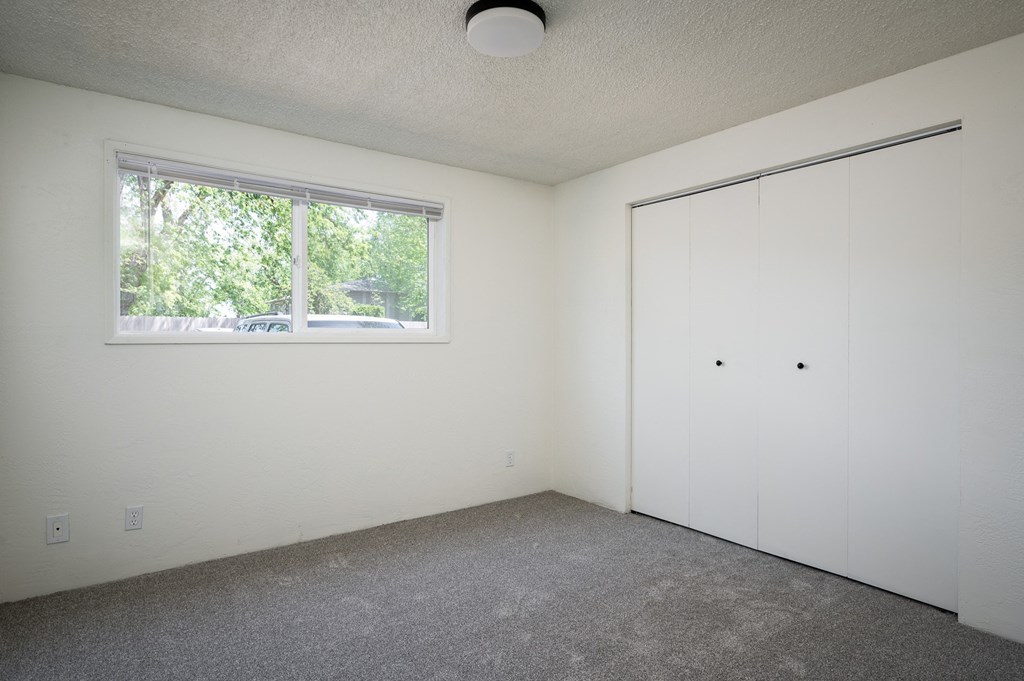 a bedroom with white walls and a window and a closet