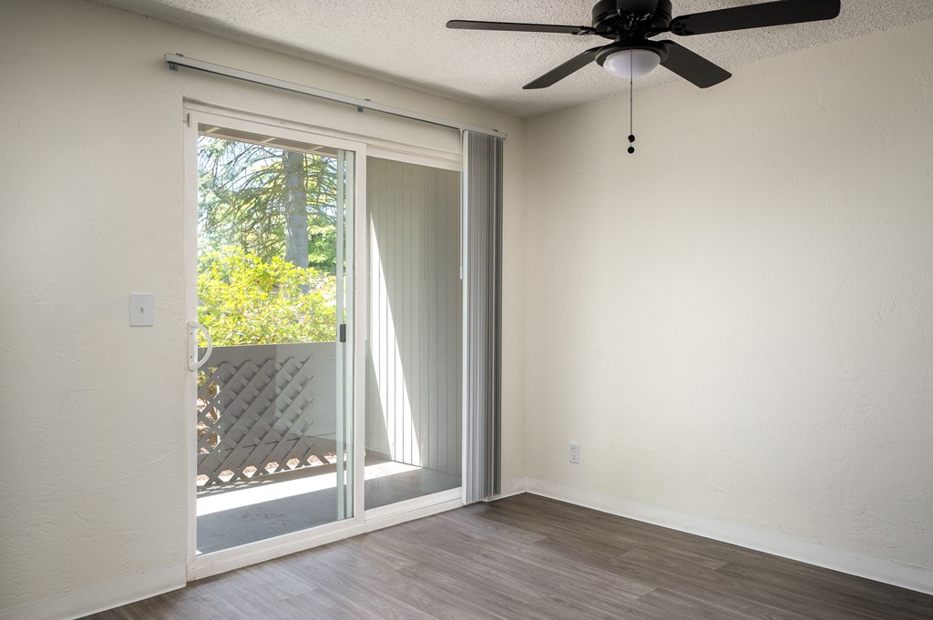 an empty room with a sliding glass door and a ceiling fan
