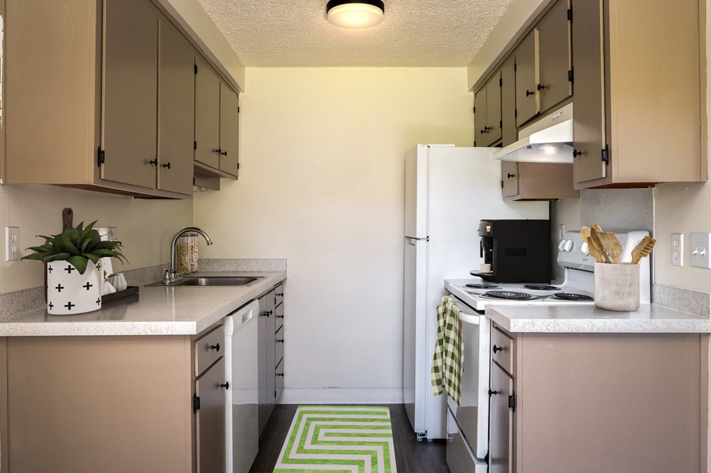 A kitchen with a white fridge and beige cabinets.
