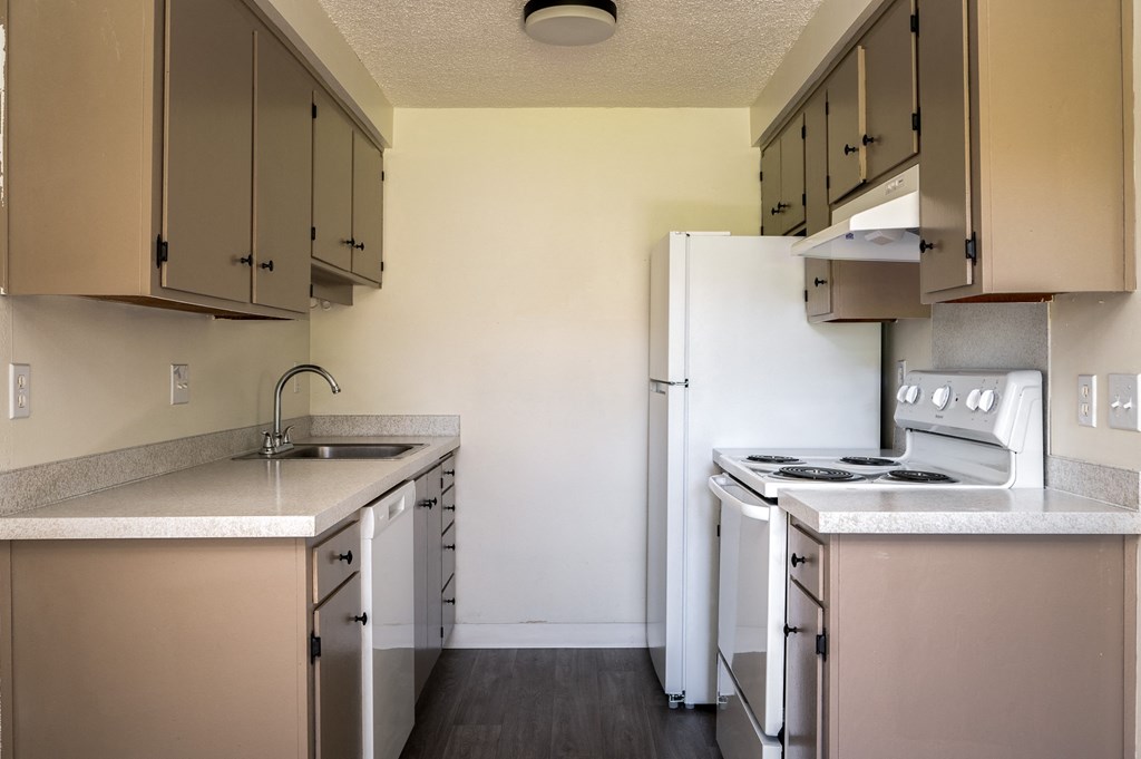 an empty kitchen with white appliances and a refrigerator