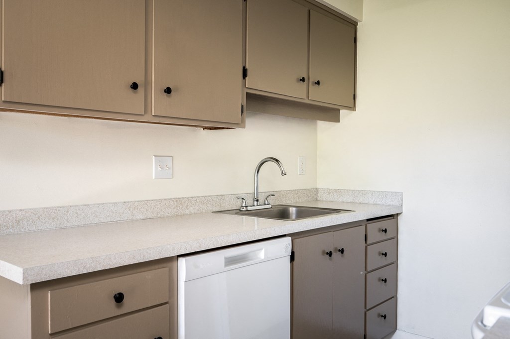 an empty kitchen with white cabinets and a sink