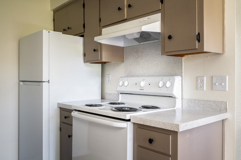 an empty kitchen with white appliances and a refrigerator