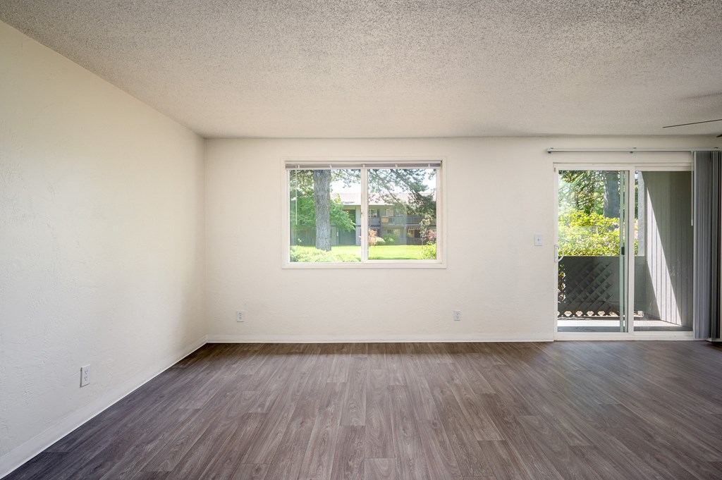 an empty living room with wood floors and a window