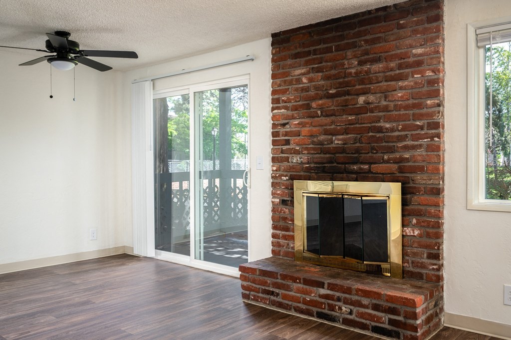 an empty living room with a brick fireplace and a sliding glass door