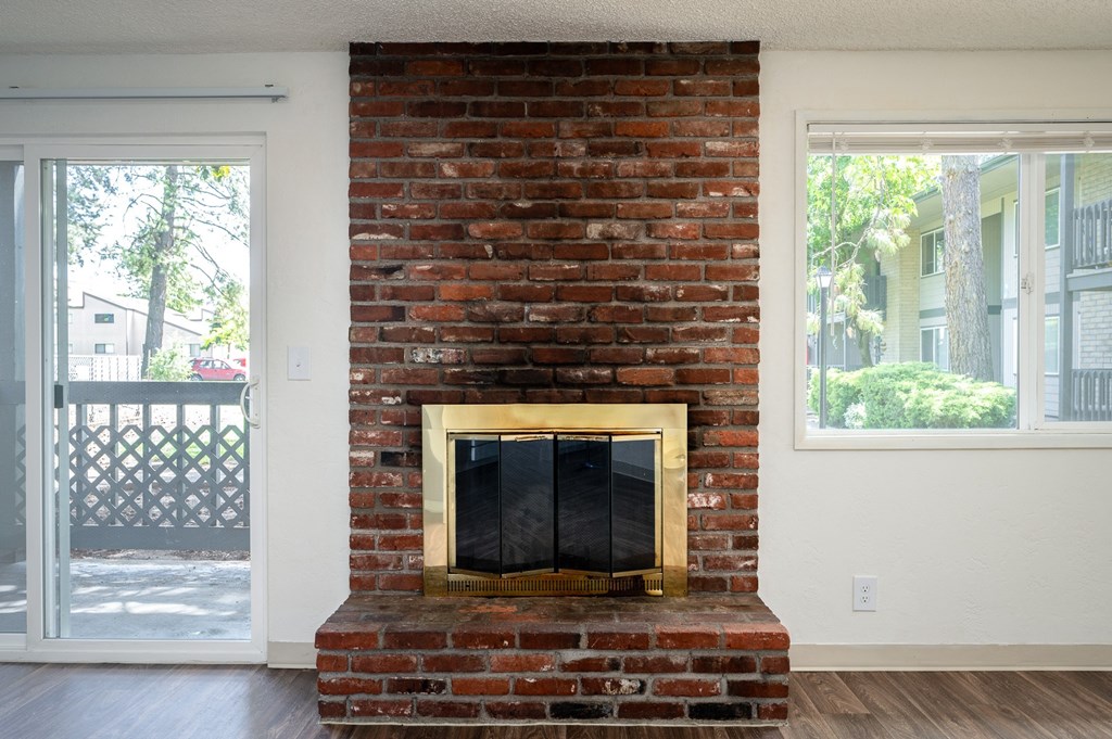 a living room with a brick fireplace and a window