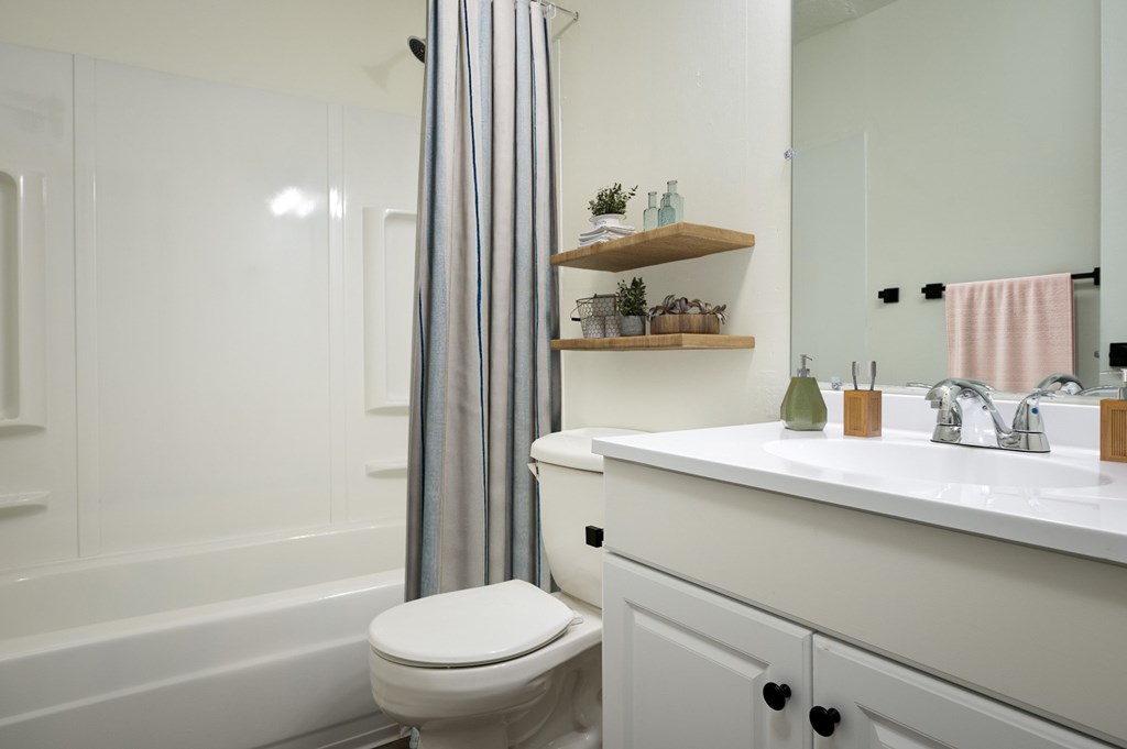 A white bathroom with a toilet, sink, and a shower curtain.