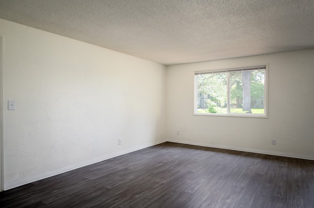 an empty living room with wood floors and a window