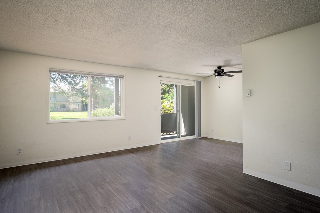 an empty living room with a window and a ceiling fan