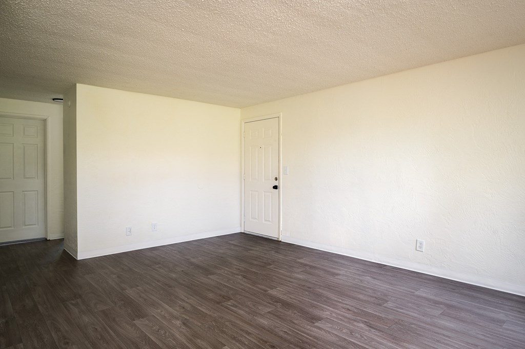 an empty living room with white walls and wood floors